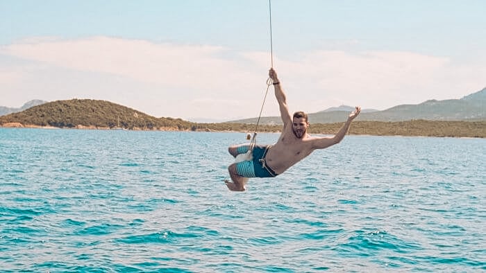 Mann springt ins Wasser über Boje vom Segelschiff in Sardinien in Italien