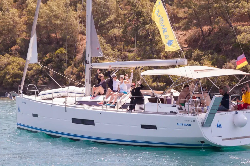 Eine Gruppe von Menschen genießt einen sonnigen Tag auf einem großen weißen Segelboot namens