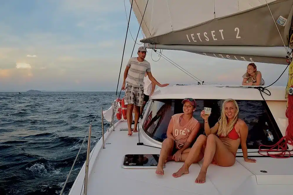 Drei Personen genießen die Zeit auf einer Segelyacht namens
