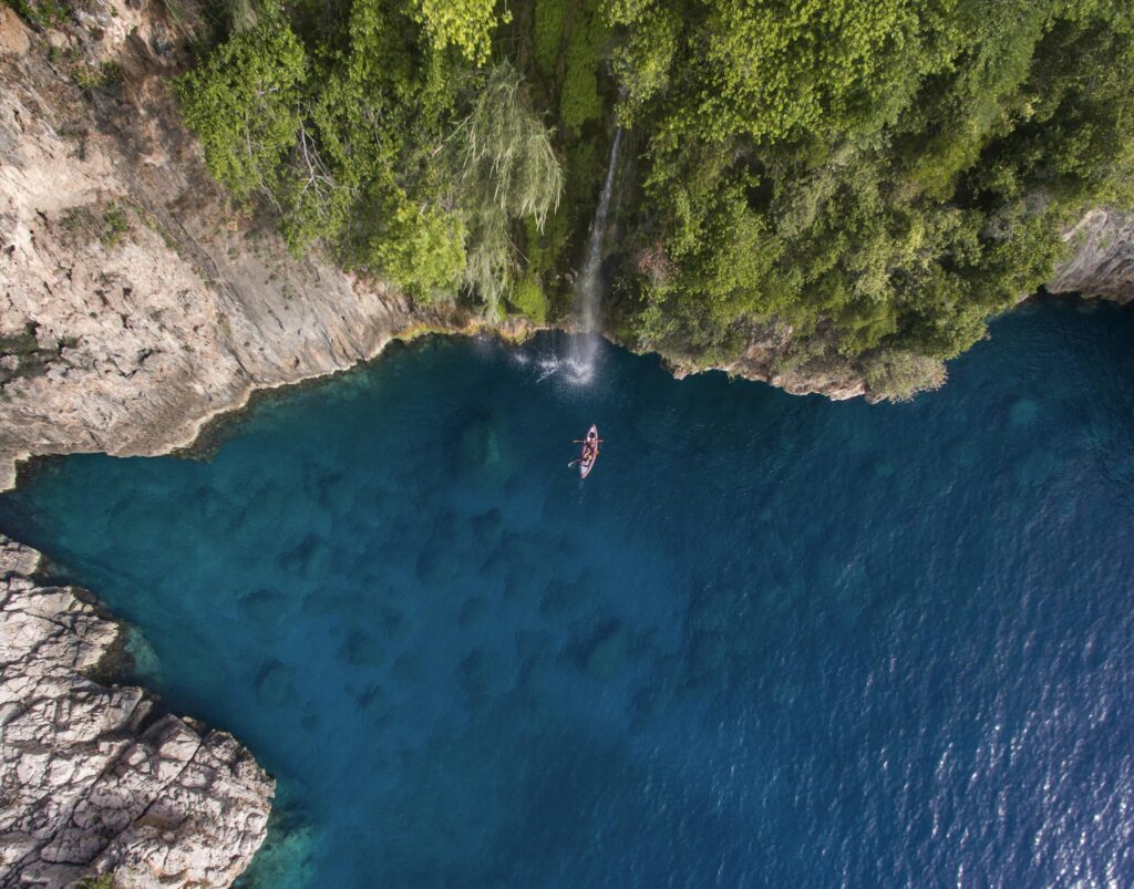 Discover the serene beauty of Fethiye's lagoon with a kayak navigating through azure waters surrounded by lush cliffs.